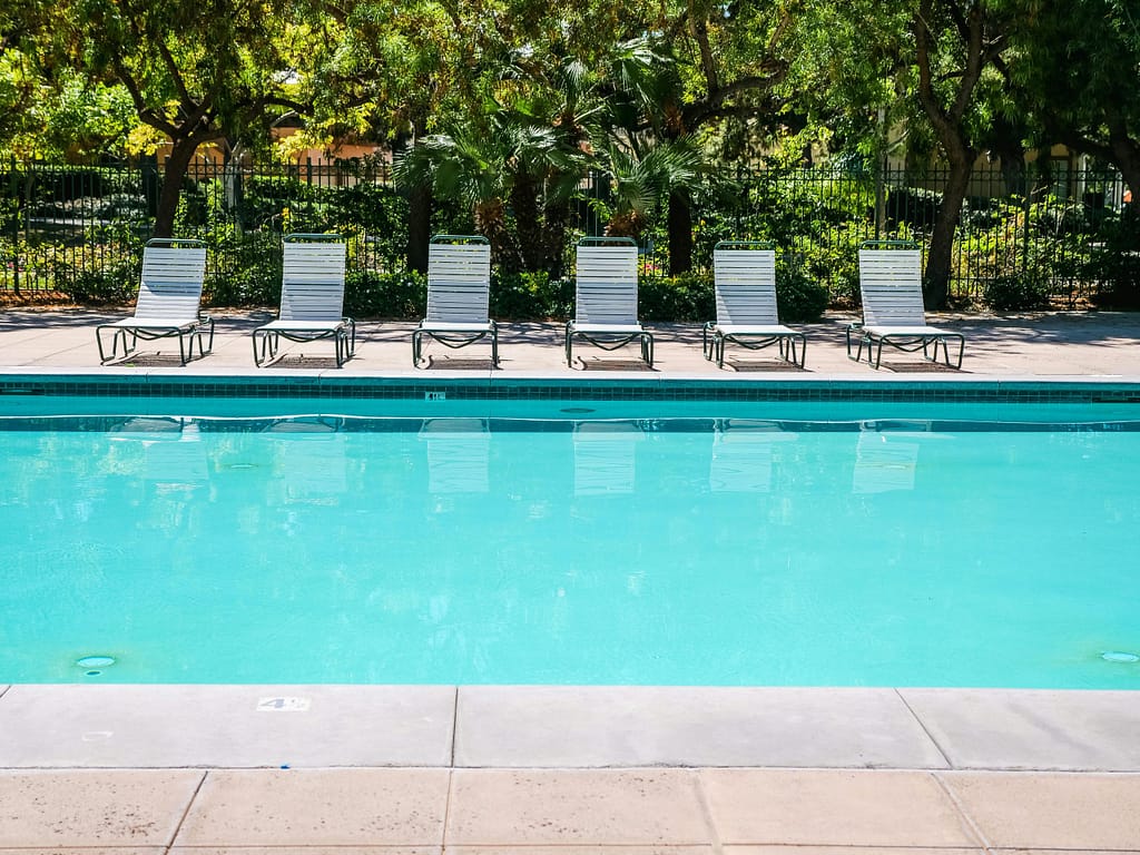 Relax by a tranquil outdoor pool surrounded by sun loungers and lush greenery.